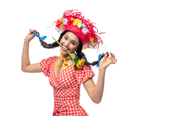 chica feliz en ropa festiva y sombrero de paja morder girasol aislado en blanco
 - Foto, Imagen