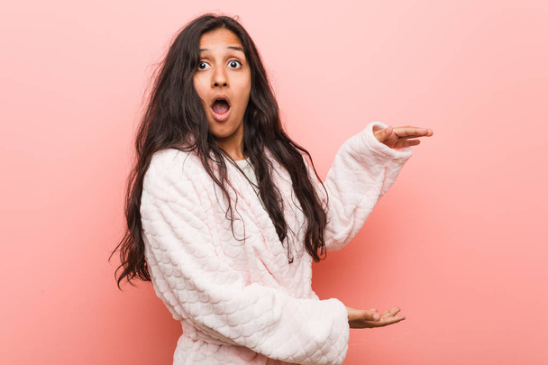 Nuori intialainen nainen yllään pyjama järkyttynyt ja hämmästynyt pitämällä kopio tilaa käsien välillä
. - Valokuva, kuva