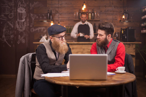 ヴィンテージレストランでビジネスミーティングをしている2人の白人男性のあごひげ - 写真・画像
