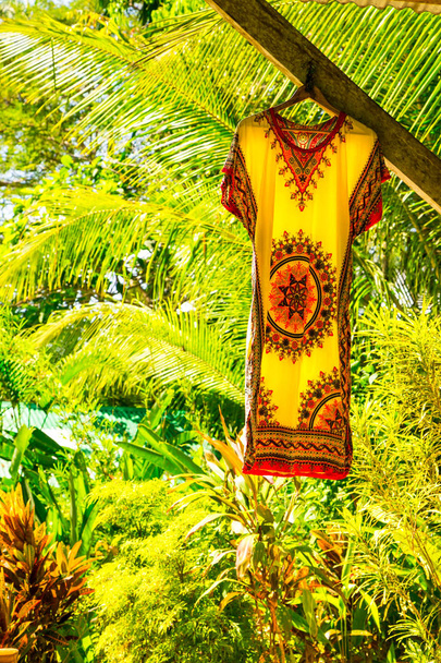 Yellow and red summer dress hanging in the garden with lush gree - Photo, Image