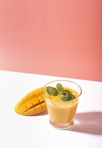 frische Mango-Smoothie und reife Mango-Scheibe auf farbigem Hintergrund.  - Foto, Bild