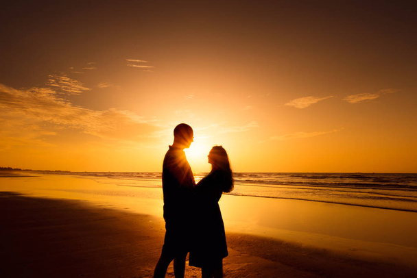 Pareja en la silueta del amor durante la puesta del sol de oro
  - Foto, imagen
