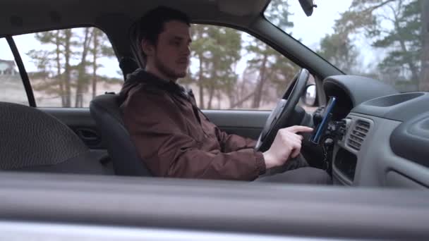 ヨーロッパの男性は、車のキャビンに座って、スマートフォンを使用します. - 映像、動画