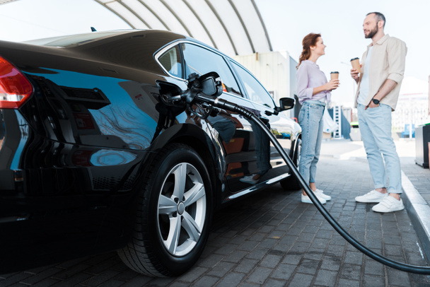 siyah araba yakıt ikmali seçici odak erkek ve kadın yakın benzine ile - Fotoğraf, Görsel