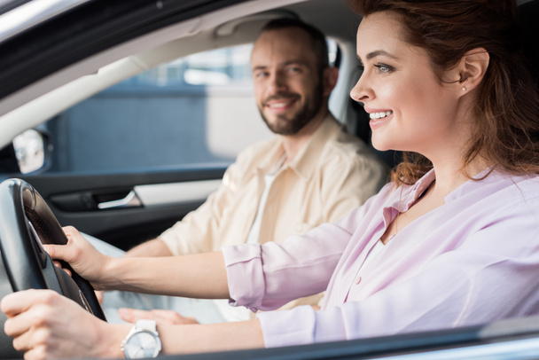 selective focus of happy woman driving car near handsome man  - Foto, afbeelding