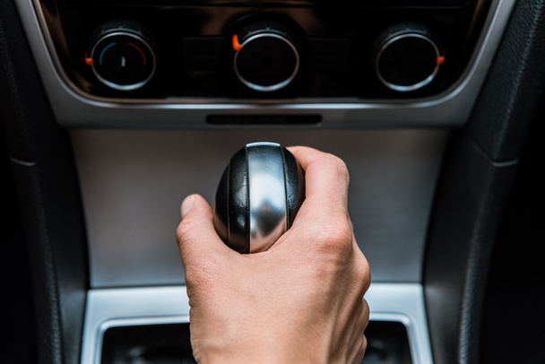 Обрезанный вид человека, держащего рукоятку переключения передач в машине
  - Фото, изображение