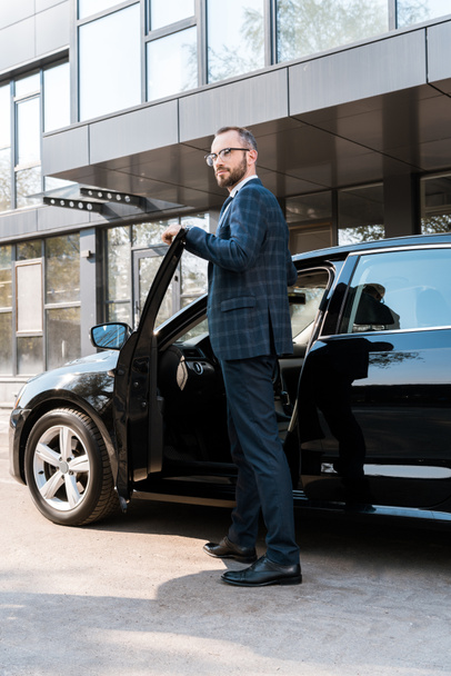 low angle view of businessman in suit standing near black car  - Foto, imagen