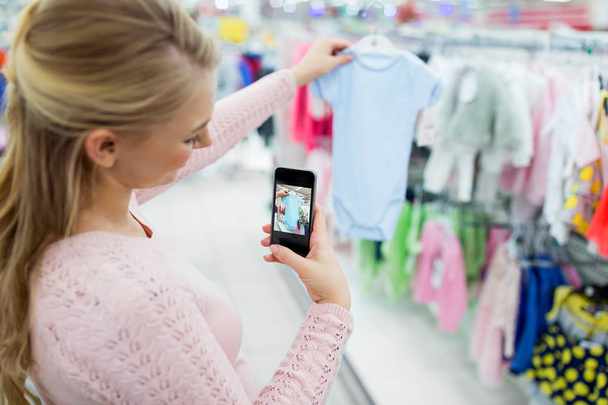 pregnant woman taking picture of baby clothes - Photo, image