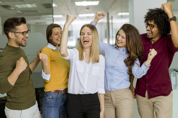 Szczęśliwe i udane młode osoby stoją w nowoczesnym biurze - Zdjęcie, obraz