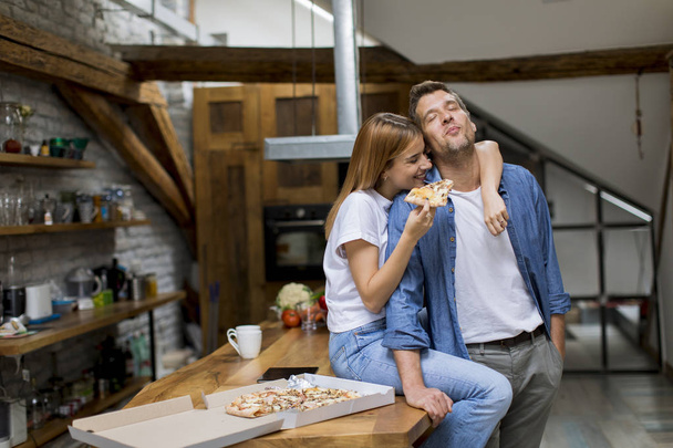 Pareja joven en el amor comer pizza para el escote en la casa rústica
 - Foto, imagen