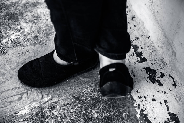 γυναικεία πόδια ή γυναικεία πόδια shod σε μαύρο χρώμα παπούτσια και μπλε χρωματιστά τζιν. - Φωτογραφία, εικόνα