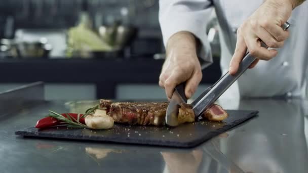 Chef hands cutting grill steak at kitchen. Closeup chef hands slicing fried meat - Felvétel, videó