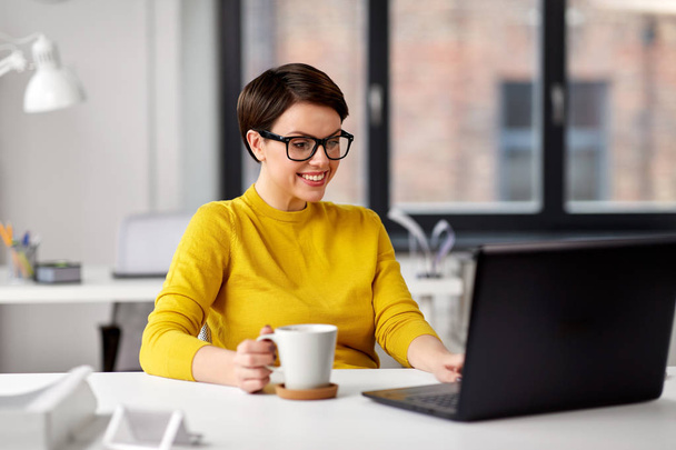 Geschäftsfrau mit Laptop trinkt Kaffee im Büro - Foto, Bild