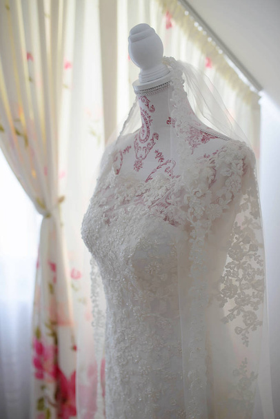 ヴィンテージマネキン胴体に設定された透明な刺繍レースコルセットを持つゴージャスな古典的なウェディングドレスや明るい窓に対するドレスフォーム、花嫁に対するユニークな前庭の作品 - 写真・画像