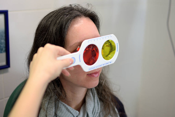 όμορφη νεαρή γυναίκα Οπτομέτρης οφθαλμολογικές εκτελεί μια δοκιμή χρώματος τύφλωση, χαμηλό βάθος πεδίου - Φωτογραφία, εικόνα