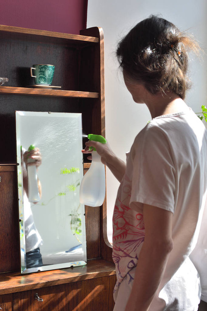 νεαρή όμορφη γυναίκα άνοιξη καθαρισμό ένα vintage καθρέφτη  - Φωτογραφία, εικόνα