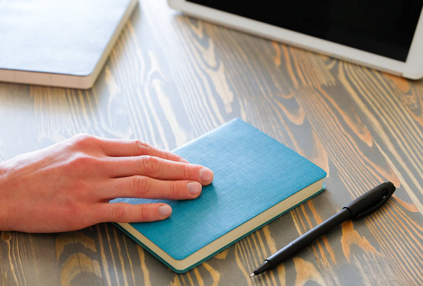 Vrouwelijke hand houdt een notebook op een werkplek achtergrond - Foto, afbeelding