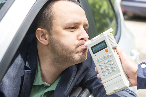 Alkoholipitoisuuden testauksen kohteena oleva kuljettaja, joka käyttää puhallustinta
 - Valokuva, kuva