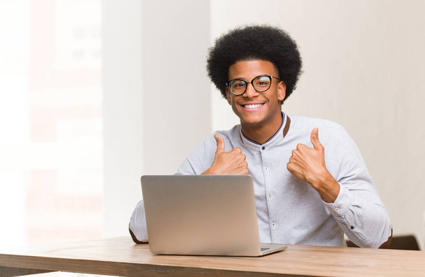 młody czarny człowiek za pomocą jego laptop zaskoczony, czuje się sukcesem i prosperuje - Zdjęcie, obraz