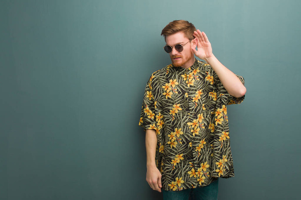 Young redhead man wearing exotic summer clothes try to listening a gossip - Photo, Image
