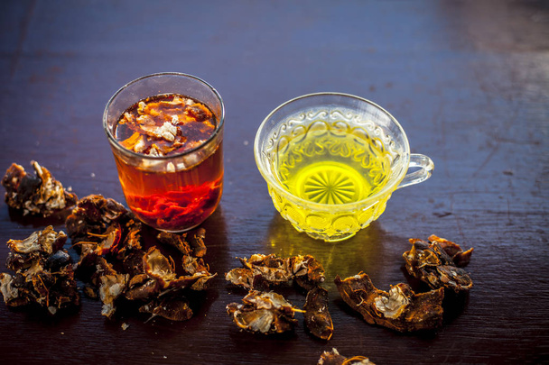 Raw organic amaltas or golden shower tree fruit on wooden surface with its extracted pulp in a glass along with water and green tea in a glass cup.Used for the treatment of worms in intestine. - Photo, Image