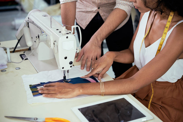Close-up beeld van twee kleermakers bespreken betere manier van naaien zijde stof op machine - Foto, afbeelding