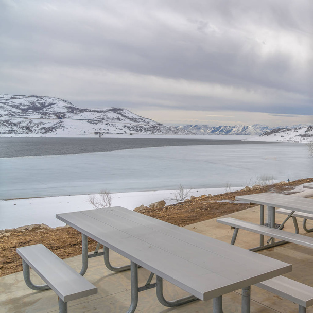 klaren quadratischen Essbereich innerhalb eines Pavillons mit Blick auf einen See inmitten der verschneiten Landschaft - Foto, Bild