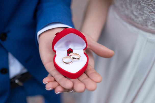 ギフトボックスに結婚指輪を持つカップルの手 - 写真・画像