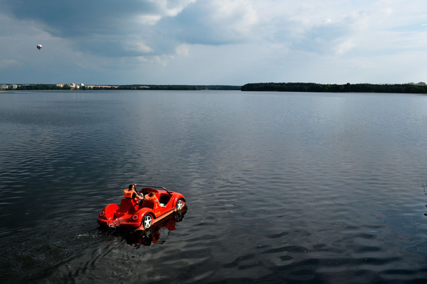 Piros autó - vízibicikli lebeg egy nyugodt tó - Fotó, kép