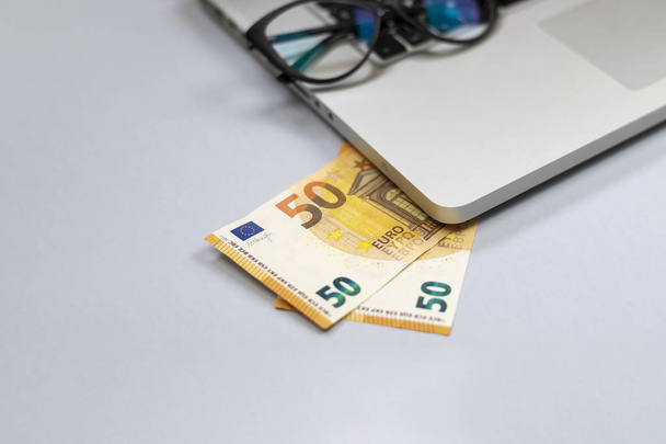 View of office desk with money, laptop, glasses - Fotografie, Obrázek
