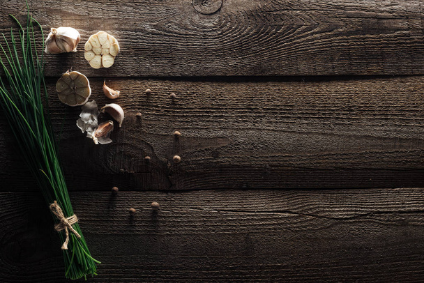 vista superior de cebolla verde, dientes de ajo y pimienta negra sobre mesa rústica de madera
 - Foto, Imagen