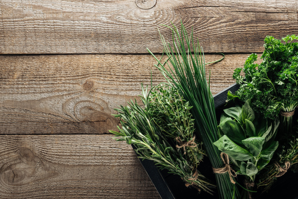 Ansicht von grünem Thymian, Spinat, Petersilie, Rosmarin und grünen Zwiebeln in Schachtel auf verwittertem Holztisch mit Kopierraum - Foto, Bild