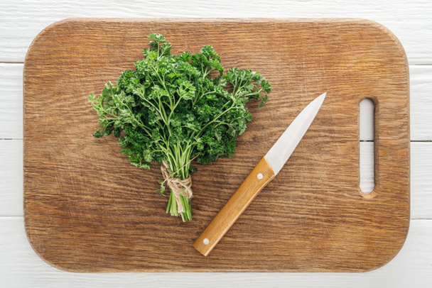 top view of green parsley and knife on wooden chopping board - Foto, Bild