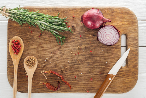 top view of various spices and rosemary near knife on wooden chopping board - Φωτογραφία, εικόνα