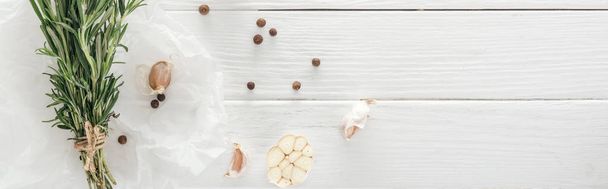 plano panorámico de dientes de ajo, pimienta negra y romero sobre mesa de madera blanca
 - Foto, imagen