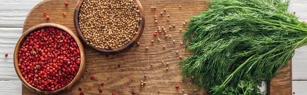 panoramic shot of coriander and pink peppercorn in bowls near green dill on wooden chopping board - Foto, imagen