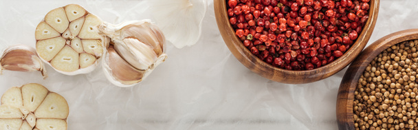 panoramic shot of garlic cloves and coriander and pink peppercorn in bowls on paper white background - Photo, Image