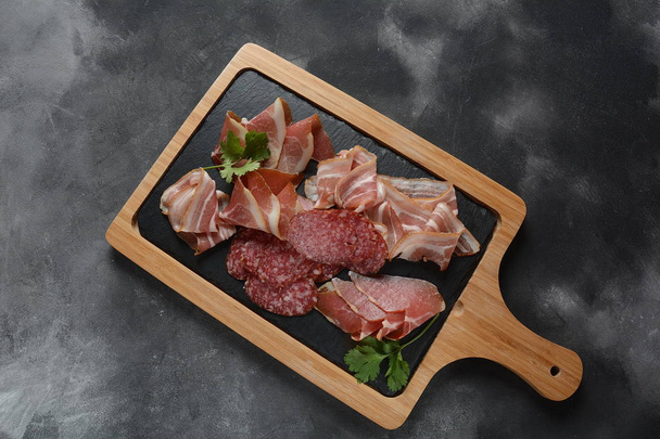 Salami, prosciutto, bacon served with melon and mint on the cutting board. Italian lunch. Delicatessen assortment of cold meat - Foto, Imagem