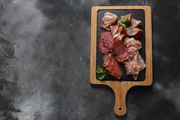 Salami, prosciutto, bacon served with melon and mint on the cutting board. Italian lunch. Delicatessen assortment of cold meat - Foto, Imagem