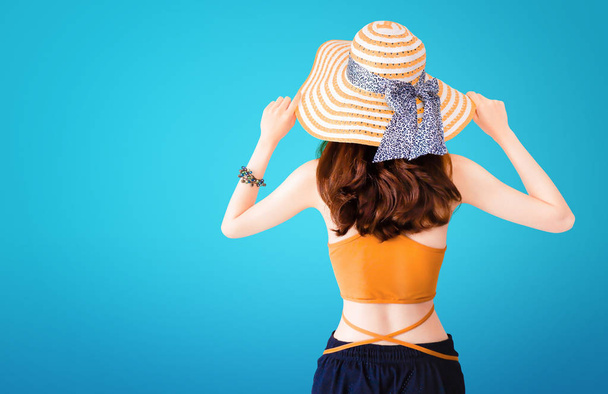 Mooie mooie vrouw het dragen van een stro hoed en sexy pak op blauwe achtergrond met zomer concept. - Foto, afbeelding