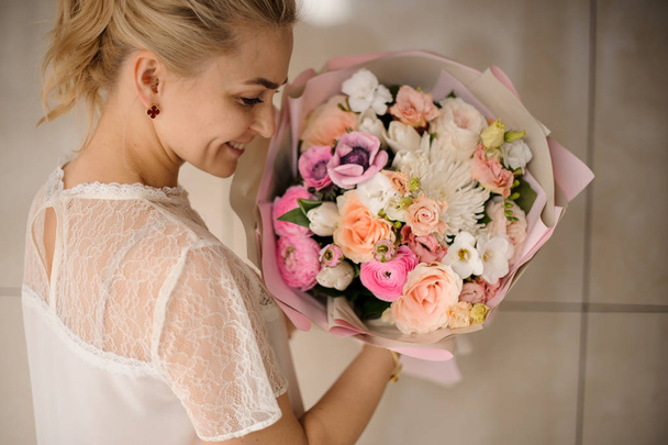 Smiling girl holding a spring bouquet of tender white and pink flowers - Foto, immagini
