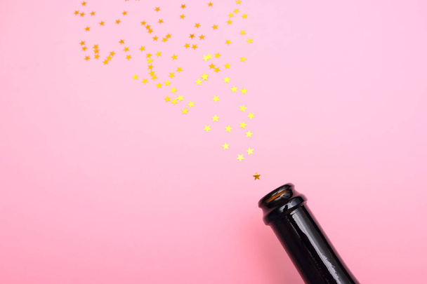 salute from sequins in the form of stars flies out of a bottle of champagne - Fotoğraf, Görsel