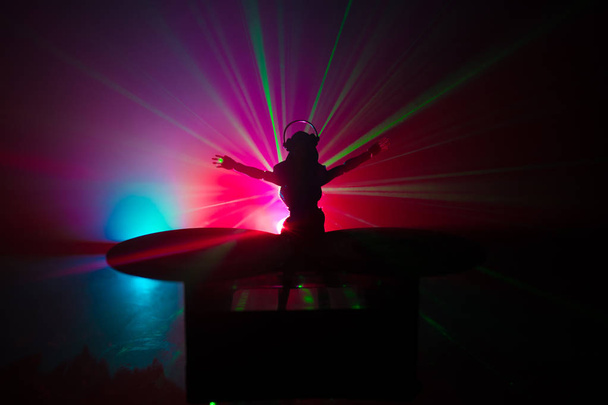 Dj club concept. Woman DJ mixing, and Scratching in a Night Club. Girl silhouette on dj's deck, strobe lights and fog on background. Creative artwork decoration with toy. Selective focus - Zdjęcie, obraz