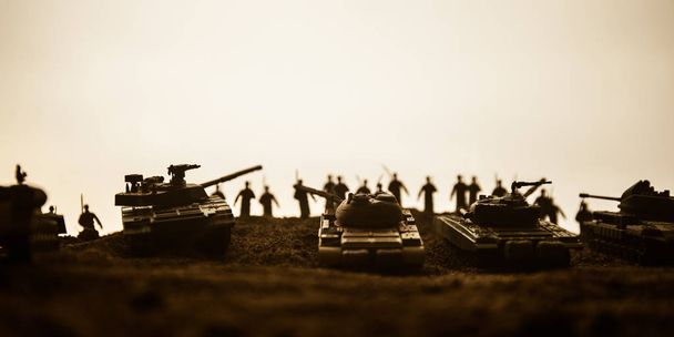 Válečný koncept. Vojenské siluety bojující s scénou na pozadí válečné mlhy, siluety světových válečných vojáků pod mračnou Skyline při západu slunce. Útočná scéna. Obrněná vozidla. - Fotografie, Obrázek
