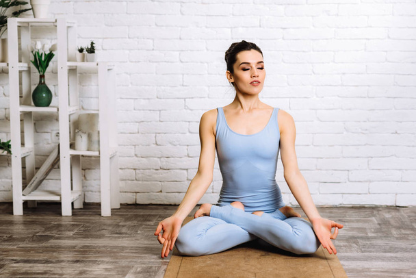 Jovem yogi mulher praticando conceito de ioga. menina vestida de sportswear azul fazendo exercício pilates no tapete
 - Foto, Imagem