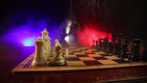 Schaken bordspel concept van bedrijfsideeën en concurrentie en strategie ideeën concep. Chess cijfers op een donkere achtergrond met rook en mist. - Video