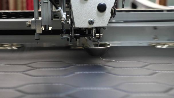 Robot naaimachine. Automatische naaimachine. Robotica werkt in de tailoring productielijn. De computer bestuurt de naaimachine. naald borduurwerk patroon op kunstleer. - Foto, afbeelding