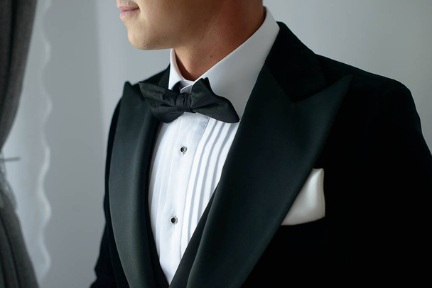 Élégant homme portant un costume de cravate noire avec chemise blanche et noeud papillon en soie et mouchoir blanc ou carré de poche, accessoires de restaurant pour une tenue formelle, un marié chic ou un homme d'affaires sophistiqué
 - Photo, image