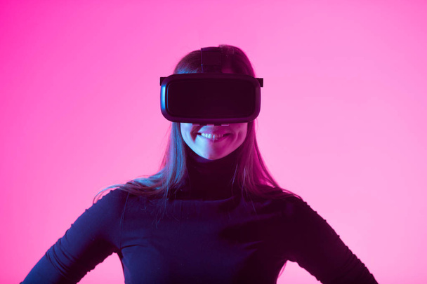 beautiful young girl wearing virtual reality glasses on a colored background - 写真・画像