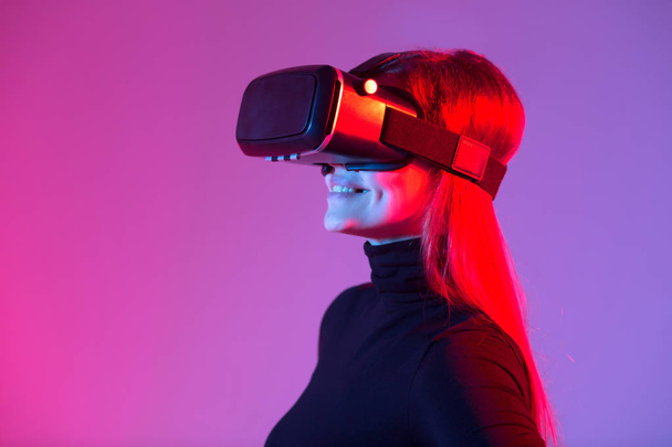 beautiful young girl wearing virtual reality glasses on a colored background - Foto, Bild